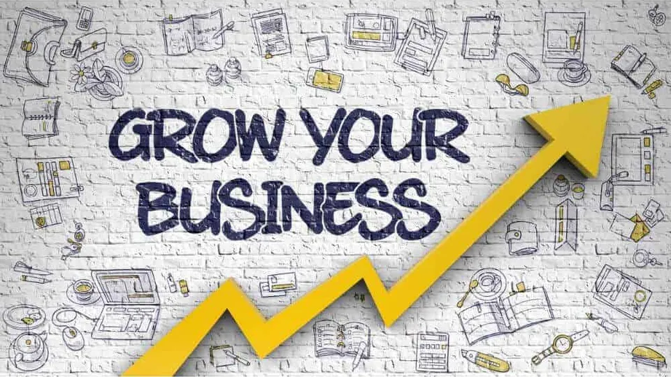 A brick wall sketched with business icons, the words GROW YOUR BUSINESS and a rising yellow arrow.